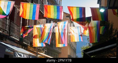 Die LGBTQ+-Flaggen leuchten bei Sonnenuntergang auf den Straßen von Chueca. Banner Stockfoto