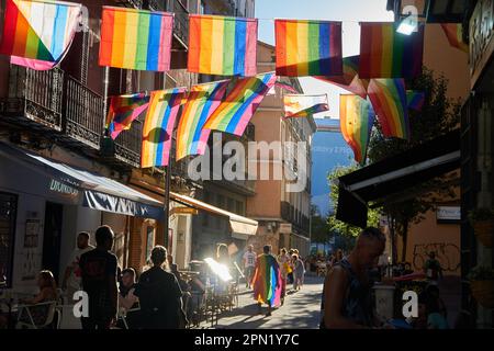 Die LGBTQ+-Flaggen leuchten bei Sonnenuntergang auf den Straßen von Chueca. Stockfoto