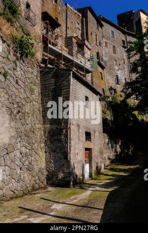 Traditionelles Hochhaus: Alte Steinbaumhäuser um den Palazzo Orsini herum, ein großer Renaissance-Dukalpalast, der in den 1500s Jahren für die reiche Familie Orsini aus einer mittelalterlichen Burg auf vulkanischem Felsen über Bomarzo, Latium, Italien, entwickelt wurde. Der Palast wurde hauptsächlich vom pensionierten Militärführer und Kunstpatron Pier Francesco Orsini, zu seiner Zeit bekannt als Vicino Orsini, erbaut. Stockfoto