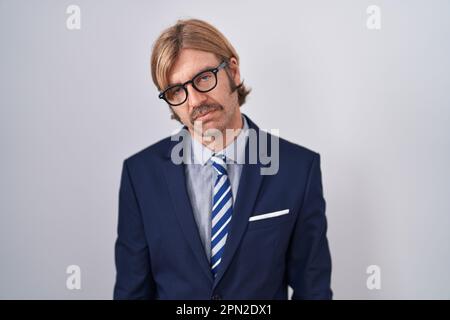 Ein weißer Mann mit Schnurrbart, der Geschäftskleidung trägt, die schläfrig und müde aussieht, erschöpft wegen Müdigkeit und Kater, faule Augen am Morgen. Stockfoto