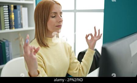 Junge blonde Studentin, die Yoga-Übungen in der Uni-Klasse macht Stockfoto