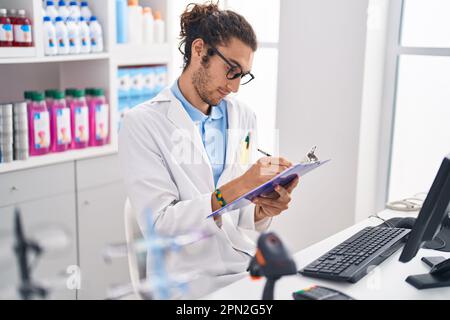 Junger hispanischer Apotheker, der auf einem Dokument in der Apotheke schreibt Stockfoto
