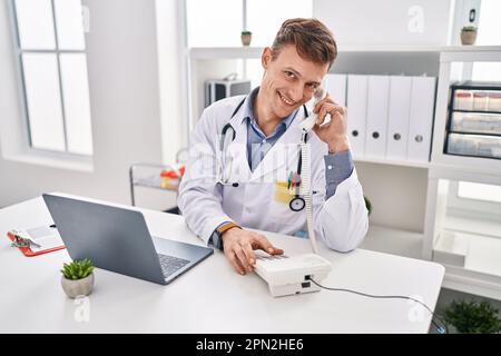 Junger Arzt mit Laptop am Telefon in der Klinik Stockfoto