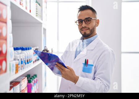 Junger hispanischer Apotheker, der auf einem Dokument in der Apotheke schreibt Stockfoto