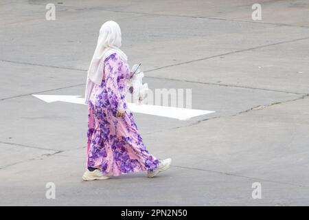 Eine Frau in kunstvoller Kleidung und einem traditionellen Hijab läuft die Straße hinunter, Thailand Stockfoto