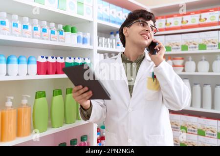 Nicht binärer Mann-Apotheker, der in der Apotheke mit dem Touchpad telefoniert Stockfoto