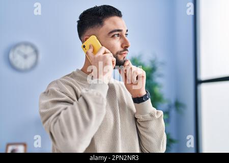Junger araber, der zu Hause mit dem Smartphone spricht Stockfoto