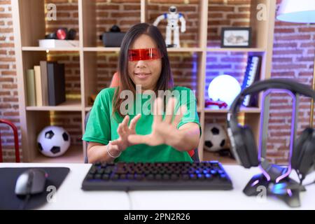 Chinesin im mittleren Alter trägt eine Virtual-Reality-Brille ekelhafter Ausdruck, verärgert und ängstlich und macht ein ekelhaftes Gesicht wegen einer Abneigungsreaktion. wi Stockfoto
