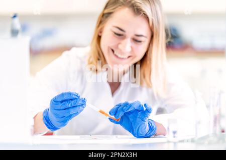 Junge Wissenschaftlerin mit einem Lächeln im Gesicht testet eine neue Erfindung in einem Forschungslabor Stockfoto