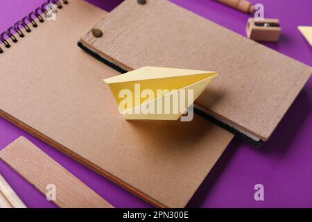 Komposition mit Schreibwaren und Papierflugzeugen auf violettem Hintergrund Stockfoto