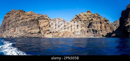 Panoramablick auf den Strand Playa de Barranco Seco am Fuße der Klippen von Acantilados de Los Gigantes mit Segelbooten im ruhigen Meer. Stockfoto