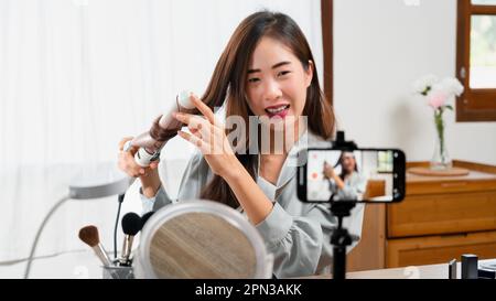 Beauty-Blogger Lockenstab mit Lockenstab und Videoaufnahme auf Smartphone für Make-up-Vlogger. Stockfoto