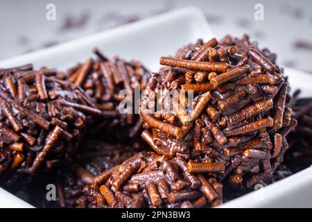 Verschiedene „brigadeiro“-Süßigkeiten in einer weißen Schüssel. Weißer Tischhintergrund. Ansicht schließen. Typisch brasilianisches Süßes. Stockfoto