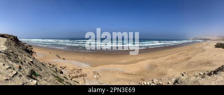 Marokko: Blick auf den Atlantik in der Nähe von Essaouira mit einigen Maultierarbeitern, die einen Strand überqueren, um Muscheln und Schalentiere aus Muscheln zu sammeln Stockfoto