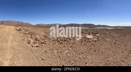 Morocco, Africa: panoramic dirt road and with on the background the view of Barrage Al-Hassan Addakhil, a light blue lake in the valley of the Ziz Stock Photo