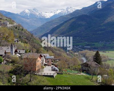 Dorf Les Grange mit seiner Kirche in der Nähe von NUS im Aosta-Tal, Italien. Die Autostrada durchschneidet das Tal mit schneebedeckten alpen dahinter. Stockfoto