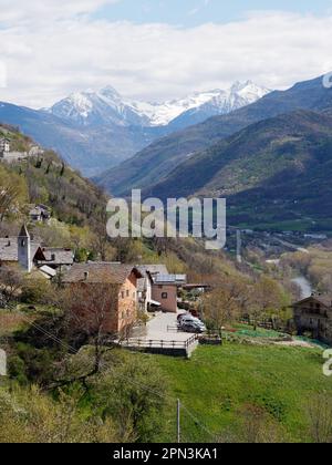 Dorf Les Grange mit seiner Kirche in der Nähe von NUS im Aosta-Tal, Italien. Die Autostrada durchschneidet das Tal mit schneebedeckten alpen dahinter. Stockfoto