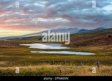 Wunderschöne Aussicht auf die Berge während einer Autotour in Island. Spektakuläre isländische Landschaft mit malerischer Natur: Berge, Felder, Wolken, Seen, Gletscher. Stockfoto