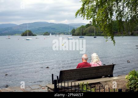 Ältere Ehepaare, die auf einer Bank am See sitzen Stockfoto