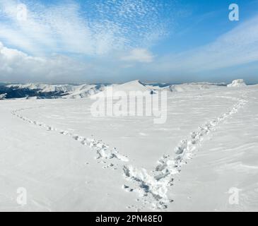 Menschlichen Fußabdruck bilden die Herzform auf schneebedeckten Berg-Plateau und Bergketten hinter. Stockfoto