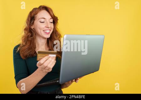 Rothaarige Frau, die online mit einem Laptop einkauft Stockfoto