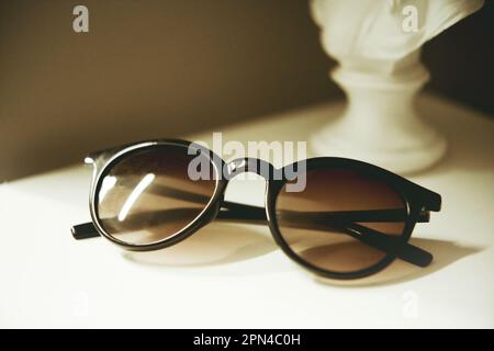 Trendige Frauen Sonnenbrillen leben immer noch in minimalistischem Stil. Modische Accessoires für den Sommer. Optikladen-Rabatt, Sonderangebot. Schließen. Selektiver Fokus. Stockfoto
