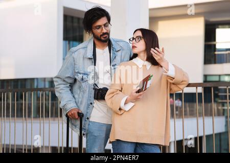 Unglücklicher, trauriger Millennials-indianer beruhigt die weiße Touristenfrau mit Pässen und Karten streiten Stockfoto