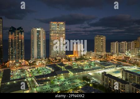 Blick auf das Stadtzentrum von Sunny Isles Beach City in Florida, USA. Hell erleuchtete Hochhäuser in der modernen amerikanischen Innenstadt Stockfoto