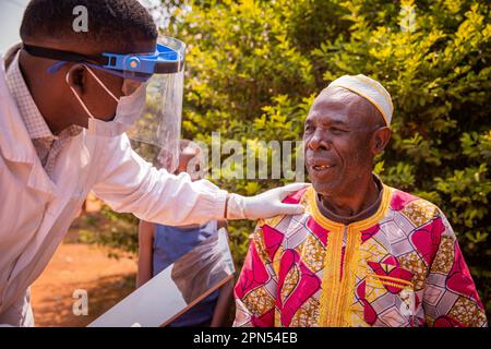 Ein afrikanischer Arzt spricht während einer ärztlichen Untersuchung mit einem älteren Patienten. Stockfoto