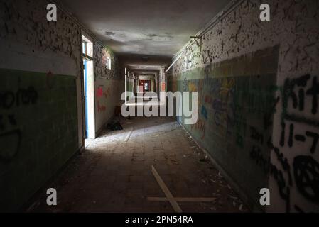 Ein dunkler Flur gefüllt mit Graffiti und schälender Farbe in einer Schule, die seit 2001 verlassen wurde. Stockfoto