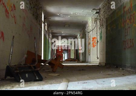 Ein dunkler Flur voller Graffiti und Trümmer in einer seit 2001 aufgegebenen Schule. Stockfoto