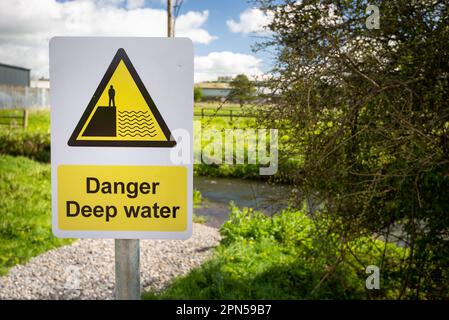 Gefahr Tiefwasser Warnschild nahe am Flussufer des ländlichen Flusses. Vorsicht, wenn man reinfällt und ertrinkt. Stockfoto