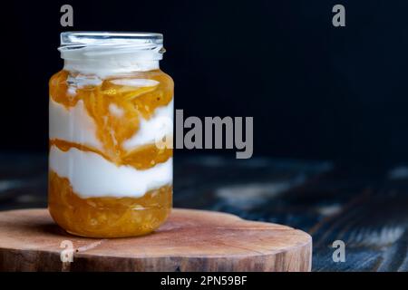 Joghurt aus frischer Milch mit süßer Zitronenmarmelade und frischen Zitronen, köstlicher Joghurt mit Zitronengeschmack Stockfoto