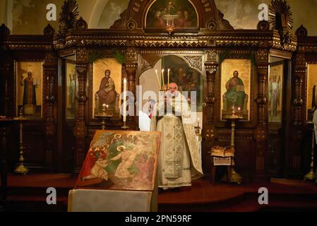 Biarritz, Frankreich. 15. April 2023. Der orthodoxe Priester Georges Ashkov, am Altar mit einem dreiarmigen Kronleuchter, verkündet die Auferstehung Christi an orthodoxen Ostern, der wichtigsten Feier orthodoxer Christen. Orthodoxe Ostern in Frankreich, in der orthodoxen Pfarrmutter Gottes und dem Heiligen Alexander von Newa. Die Gläubigen der orthodoxen Kirche feiern die Auferstehung Jesu Christi, gehen zur Kirche, um die heiligen Riten zu beten, bringen Essen und Trinken, um gesegnet zu werden. Es ist der wichtigste Akt der orthodoxen christlichen Riten. (Kreditbild: © Elsa A Bravo/SOPA Images Stockfoto