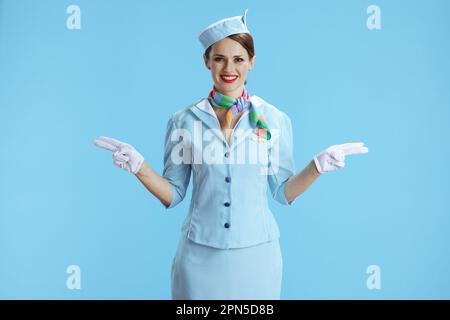 Fröhliche, elegante Stewardess, isoliert auf blauem Hintergrund in blauer Uniform. Stockfoto