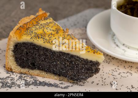 Ein geschnittenes Stück Kuchen mit Mohnsamen Füllung, eine dicke Schicht Mohnsamen, die sich zwischen dünnen Schichten von Schwammkuchen im Dessert füllt Stockfoto