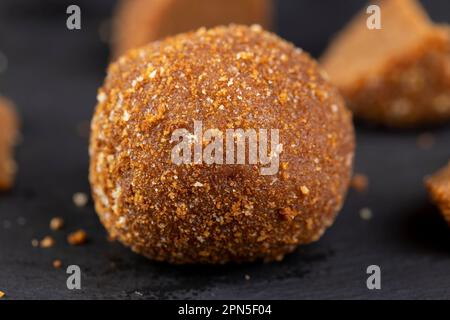 Köstliche runde Schokoladenbonbons aus Kakao und Zucker, köstliche kleine Süßigkeiten auf einem schwarzen Schieferbrett Stockfoto