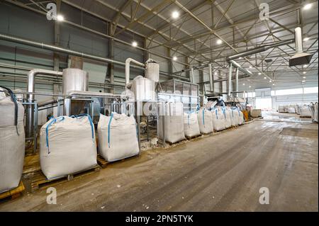 Riesige Plastiktüten mit Produkten auf Paletten in der Recyclingfabrik Stockfoto