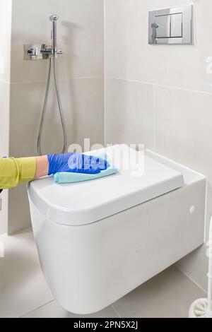 Wandmontierte Toilettenreinigung. Das Zimmermädchen reinigt die Toilette mit einer Bürste. Frauenhaushaltsdienst Stockfoto