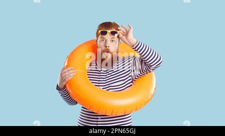 Erstaunlicher, flippiger, verrückter Mann mit aufblasbarem Schwimmkreis, isoliert auf pastellfarbenem türkisfarbenem Hintergrund. Stockfoto