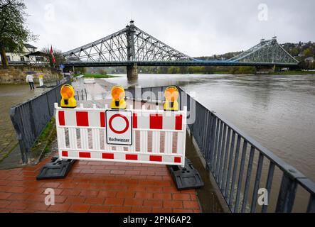 Dresden, Deutschland. 17. April 2023. Ein Schild auf einer Barriere warnt vor Hochwasser auf dem Elbradrennweg vor dem Schillergarten in der Nähe der Loschwitz-Brücke, besser bekannt als das Blaue Wunder. Die Höhe der Elbe in Dresden beträgt derzeit 4,08 Meter. Kredit: Robert Michael/dpa/Alamy Live News Stockfoto