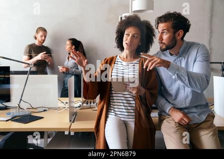 Lächelnd treffen sich verschiedene Kollegen in einem Brainstorming in der Vorstandsetage, um gemeinsam Finanzstatistiken zu diskutieren Stockfoto