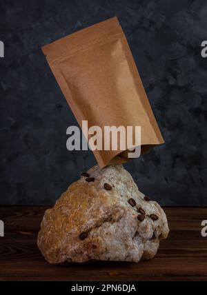 Balanciertaschen-Modell auf Naturstein. Leere Kraftpapierpackung mit dunklem Hintergrund für Kaffeebohnen. Gleichgewichtsschwankungen. Werbung für Lebensmittel Stockfoto