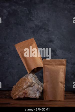 Balanciertaschen-Modell auf Naturstein. Leere Kraftpapierpackung mit dunklem Hintergrund für Kaffeebohnen. Gleichgewichtsschwankungen. Werbung für Lebensmittel Stockfoto