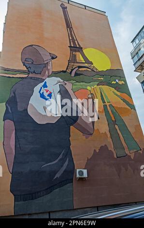 Ein romantischer Typ mit Plastiktüte hinter seinem Traum von Paris. Zeichnung an der Wand eines mehrstöckigen Wohngebäudes. Dnipro, Ukraine - März Stockfoto