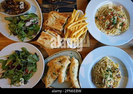 Balsamico-Salat mit Rucola und Knoblauchbrot mit Meeresfrüchten, Carbonara-Pasta und Pommes Frites mit französischem Kartoffelkeil Stockfoto