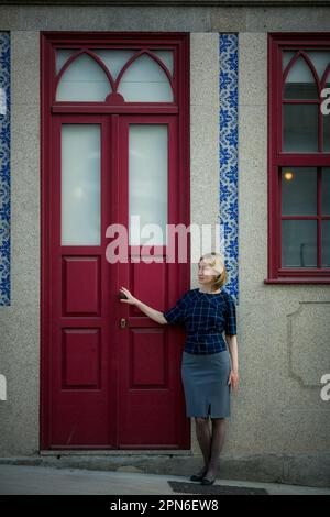 Eine Frau steht neben der Eingangstür eines Wohngebäudes in Porto, Portugal. Stockfoto