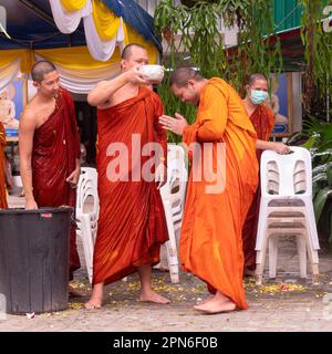 Ban Chang, Thailand - 16. April 2023: Mönche gießen Wasser mit Blütenblättern über einander, um Songkran, das buddhistische Neujahr, im Wat Chak Mak zu feiern Stockfoto