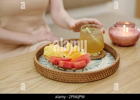 Eine Tasse Eistee und frisches Obst auf dem Tablett vor dem Gast des Spa-Salons Stockfoto