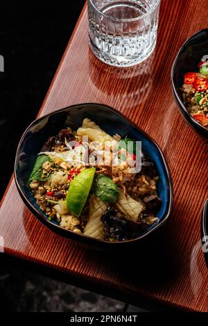 Gebratener chinesischer Reis mit Tintenfisch, Gemüse und Kräutern. Restaurant Stockfoto